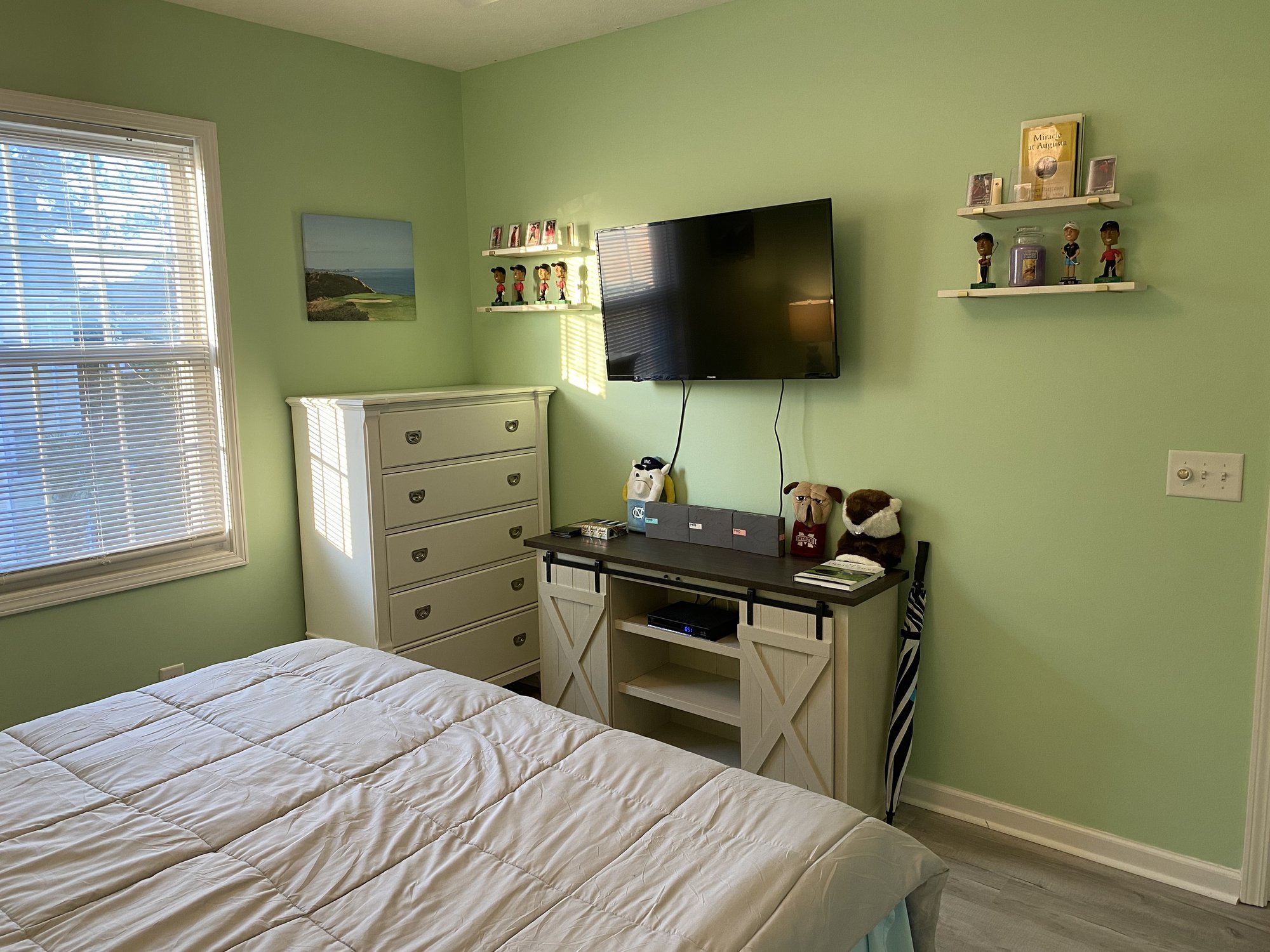 Golf-themed bedroom TV dresser and bobbleheads at 601 Hillside Dr N