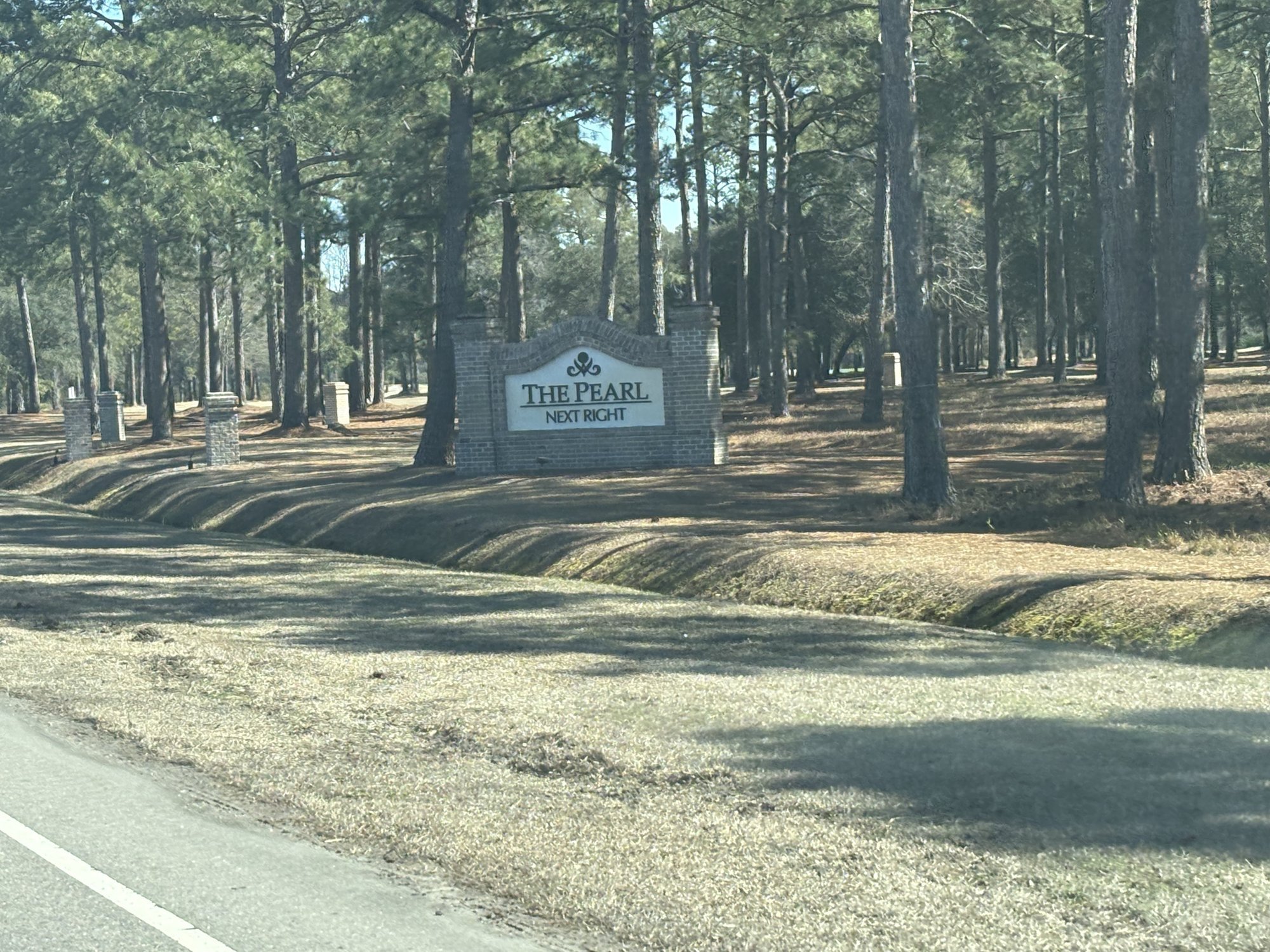 The Pearl Golf Links entrance sign among longleaf pines in Sunset Beach NC