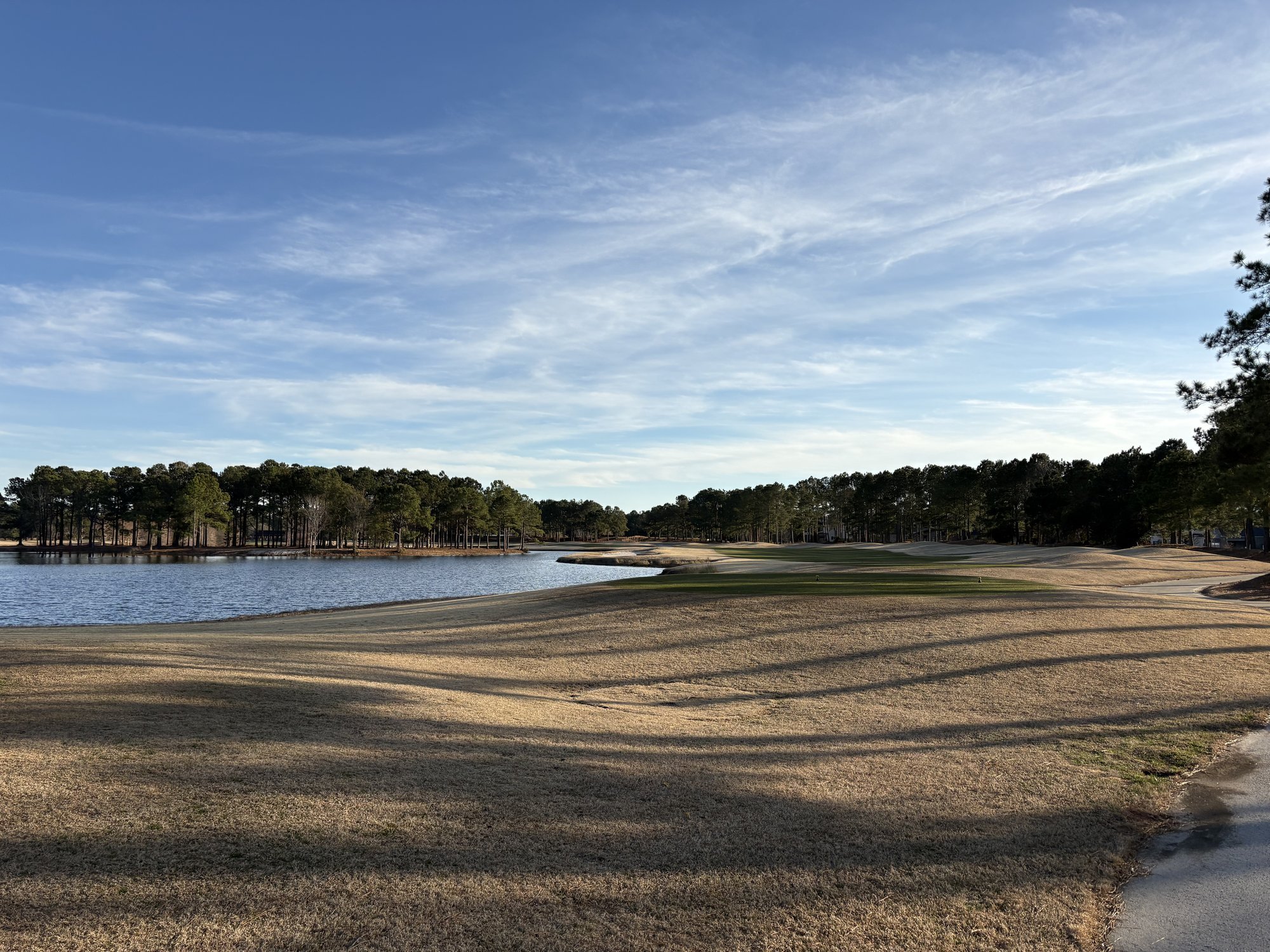 Late afternoon shadows across McKay nine fairway at Thistle Golf Club with lake and pines Sunset Beach NC
