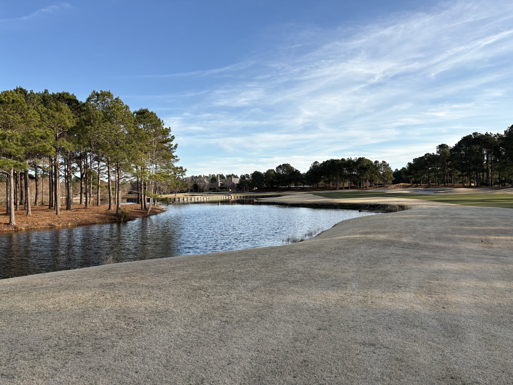 Sweeping fairway along lake with pines and wispy clouds on McKay nine at Thistle Golf Club Sunset Beach NC